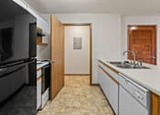 Thumbnail 58 of 64 - A kitchen with a black refrigerator and white countertops.