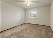 Thumbnail 45 of 64 - A room with a carpeted floor and a window showing a building outside.