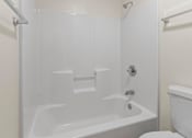 Thumbnail 62 of 64 - A white bathtub with a shower head and a toilet in a bathroom.