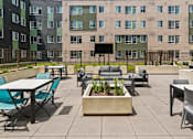 Thumbnail 9 of 56 - A patio with tables and chairs and a planter in the middle.