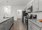 Thumbnail 24 of 38 - A kitchen with a black fridge and a black stove top.