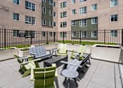 Thumbnail 10 of 56 - A patio with a table and chairs is in front of a building.