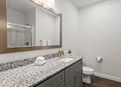 Thumbnail 32 of 38 - A bathroom with a granite countertop and a mirror above it.