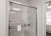 Thumbnail 33 of 38 - A white bathroom with a glass shower door and a towel hanging on a bar.