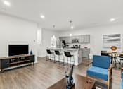 Thumbnail 21 of 38 - A modern living room with a television, chairs, and a dining area.