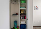 Thumbnail 44 of 56 - A closet with clothes and a basket on the floor.