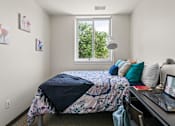 Thumbnail 29 of 56 - A bedroom with a bed, desk, and laptop.