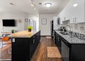 Thumbnail 34 of 56 - A modern kitchen with black cabinets and a granite countertop.