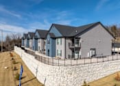 Thumbnail 6 of 38 - A row of houses with grey roofs and a stone wall in front.