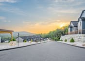 Thumbnail 16 of 38 - A residential street with houses on both sides and a clear sky.