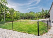 Thumbnail 15 of 38 - A backyard with a fenced green lawn and trees.