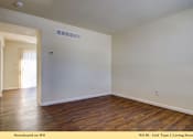 Thumbnail 12 of 35 - A living room with wooden floors and white walls.