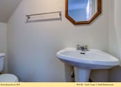 Thumbnail 14 of 35 - A white sink in a small bathroom with a toilet and a mirror.