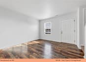 Thumbnail 21 of 35 - A living room with wooden floors and white walls.