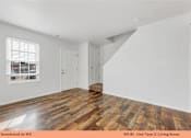 Thumbnail 20 of 35 - A living room with wooden flooring and white walls.