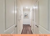 Thumbnail 8 of 31 - a hallway with white doors and white walls and wood floors