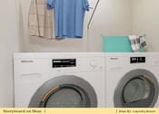 Thumbnail 20 of 31 - a white washer and dryer in a laundry room with a blue shirt hanging