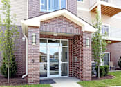 Thumbnail 5 of 23 - The front of a brick building with a glass door and windows.