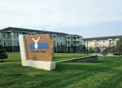 Thumbnail 1 of 23 - A sign for Eco Hills Apartment Homes sits in front of apartment buildings.
