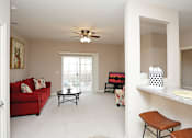 Thumbnail 14 of 23 - A living room with a red couch, a coffee table, and a ceiling fan.