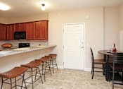 Thumbnail 11 of 23 - A kitchen with brown bar stools and a white door.