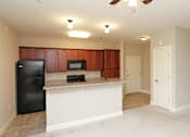 Thumbnail 15 of 23 - A kitchen with brown cabinets and a black refrigerator.
