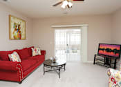 Thumbnail 17 of 23 - A living room with a red couch and a painting of an owl on the wall.