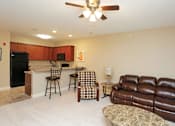 Thumbnail 6 of 23 - A living room with a brown leather couch and a bar area.