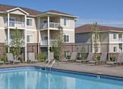 Thumbnail 2 of 23 - A swimming pool is in front of apartment buildings.