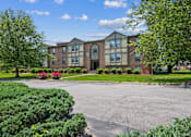 Thumbnail 1 of 21 - A large building with a red brick facade and a green lawn in front.
