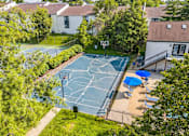Thumbnail 19 of 20 - A basketball court surrounded by trees and a fence.