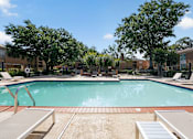 Thumbnail 23 of 30 - A large outdoor swimming pool surrounded by trees and lounge chairs.