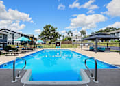 Thumbnail 25 of 27 - A large swimming pool surrounded by a fence and lounge chairs.