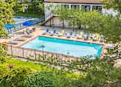 Thumbnail 1 of 20 - A pool surrounded by trees and chairs.