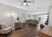 Thumbnail 8 of 32 - Living room at Renaissance at Carol Stream featuring a chair, plant, and ceiling fan in Carol Stream, IL.