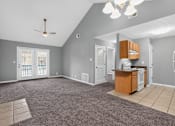 Thumbnail 1 of 18 - A spacious living room with a kitchenette and a ceiling fan.