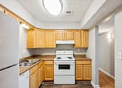Thumbnail 10 of 21 - A kitchen with wooden cabinets and a white stove top oven.