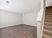 Thumbnail 4 of 25 - A room with a staircase and wooden flooring.
