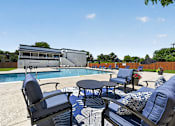 Thumbnail 26 of 32 - Poolside seating area at Renaissance at Carol Stream featuring blue chairs and a table in Carol Stream, IL.