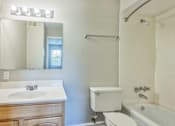 Thumbnail 13 of 21 - A white bathroom with a sink, toilet, and bathtub.
