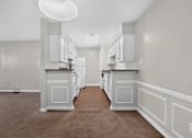 Thumbnail 13 of 30 - A kitchen with white cabinets and a brown carpet.