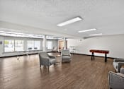 Thumbnail 17 of 34 - A room with wooden floors and white walls has a piano and several chairs.