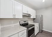 Thumbnail 2 of 25 - A kitchen with white cabinets and a stove top oven.