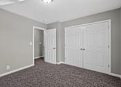 Thumbnail 10 of 18 - A room with a carpeted floor and two white doors.