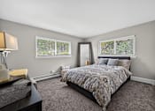 Thumbnail 9 of 32 - Bedroom at Renaissance at Carol Stream featuring a bed, nightstand, and window with blinds in Carol Stream, IL.