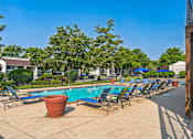 Thumbnail 13 of 20 - A pool area with chairs and a potted plant.
