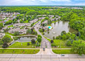 Thumbnail 29 of 31 - A bird's eye view of a residential area with a lake and greenery.