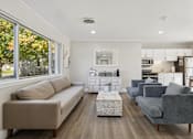 Thumbnail 16 of 26 - A living room with a grey couch and a coffee table.