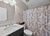 Thumbnail 10 of 32 - Bathroom at Renaissance at Carol Stream featuring a floral shower curtain and white toilet in Carol Stream, IL.