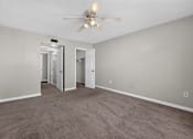 Thumbnail 16 of 30 - A room with a ceiling fan and carpeted floor.